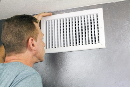 man inspecting air vent and checking the airflow